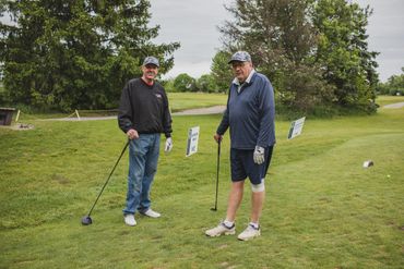 Two men standing on a golf course holding golf clubs.