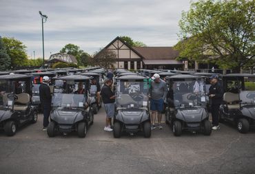 Golfers preparing with golf carts outside a clubhouse on a cloudy day.