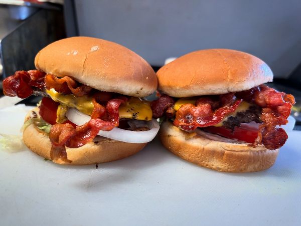 Two bacon cheeseburgers sitting on sandwich board