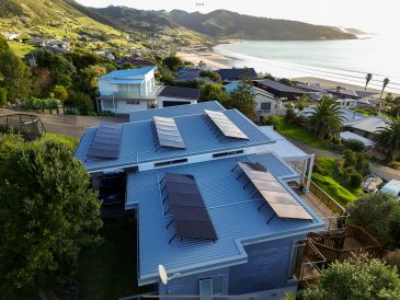 Modern house with solar panels on the roof near the beach.