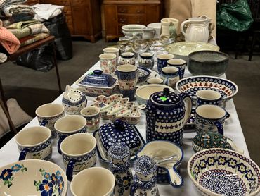 A table displaying assorted ceramic dishes and cups with floral and patterned designs.