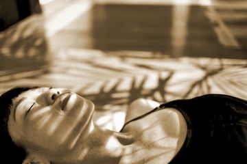Person peacefully lying down with shadow patterns on face.