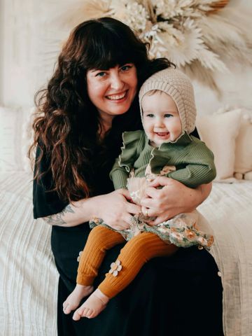 Smiling woman hugging a happy baby indoors.