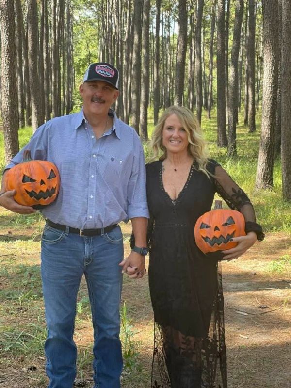Couple holding carved pumpkins in a forest.