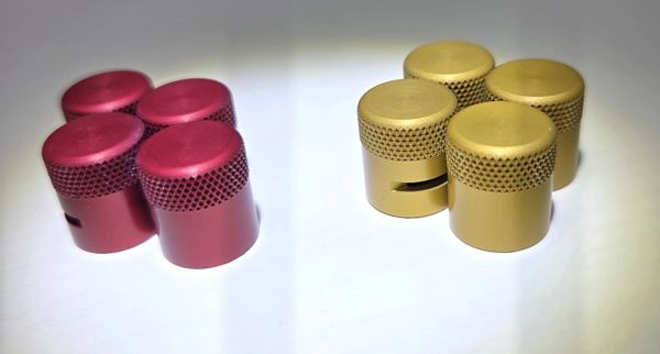Four red and four gold metal knobs with textured grips on a white surface.
