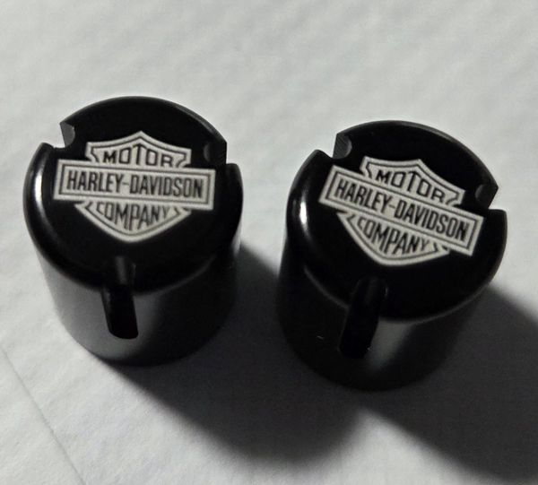 Two black Harley-Davidson branded caps or knobs.