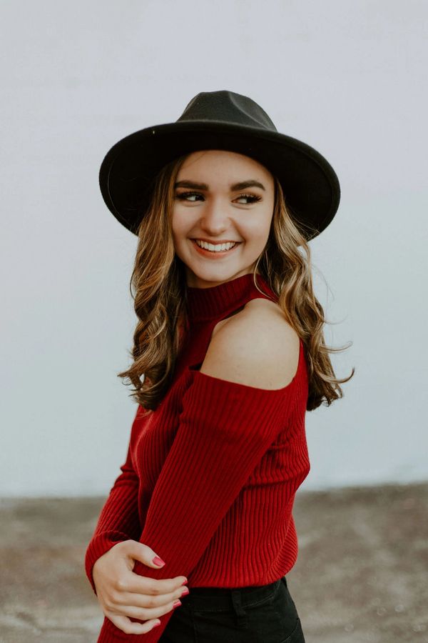 Smiling woman in a red sweater and black hat.