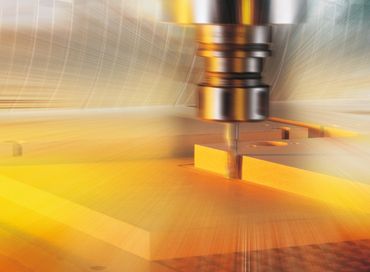 High-speed CNC milling machine carving a metal workpiece with dynamic motion blur.