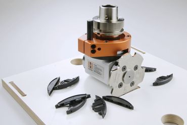 Precision woodworking tool with black plastic pieces on a white board.