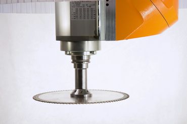Close-up of an orange and silver industrial machine with a circular saw blade.