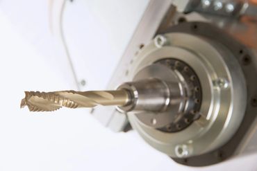 Close-up of a metal drill bit attached to a CNC machine spindle.