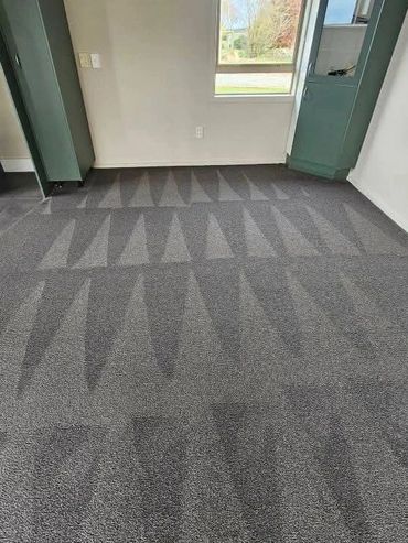 Newly vacuumed carpet with triangular pattern marks in an empty room.