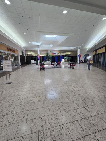 Empty shopping mall corridor with a few people sitting and walking.