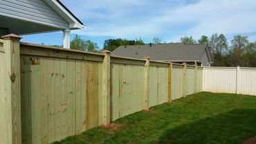 A newly built wooden privacy fence in a backyard on a sunny day.