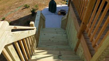 Newly built wooden stairs leading down to a backyard patio.