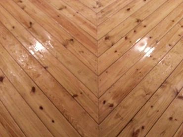 Polished wooden floor with a chevron pattern reflecting light.