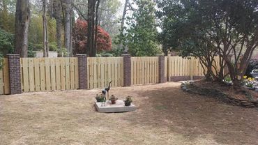 Backyard with wooden and brick fence, lawn, and decorative metal bird sculptures.