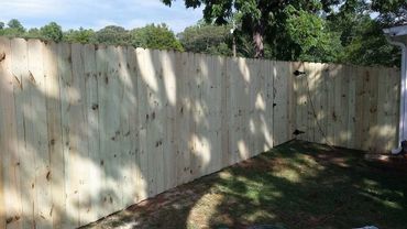 Newly installed wooden fence in a backyard on a sunny day.