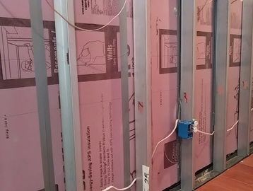 Interior wall framing with pink insulation board.