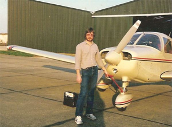 Clarke beside his light aircraft in the 1980's on a tarmac outside a hangar