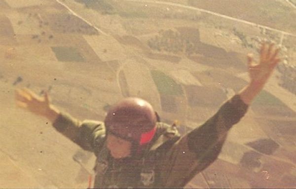 AFN Clarke jumping from a plane in British Parachute Regiment uniform arms outstretched