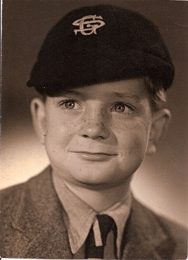 Clarke's photo as a small boy, smiling face with school cap, sepia toned