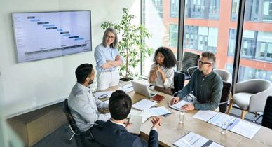 A team discussing a project timeline in a modern office meeting room.