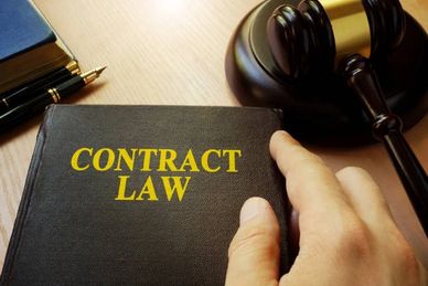 A hand holding a book titled 'Contract Law' beside a judge's gavel.