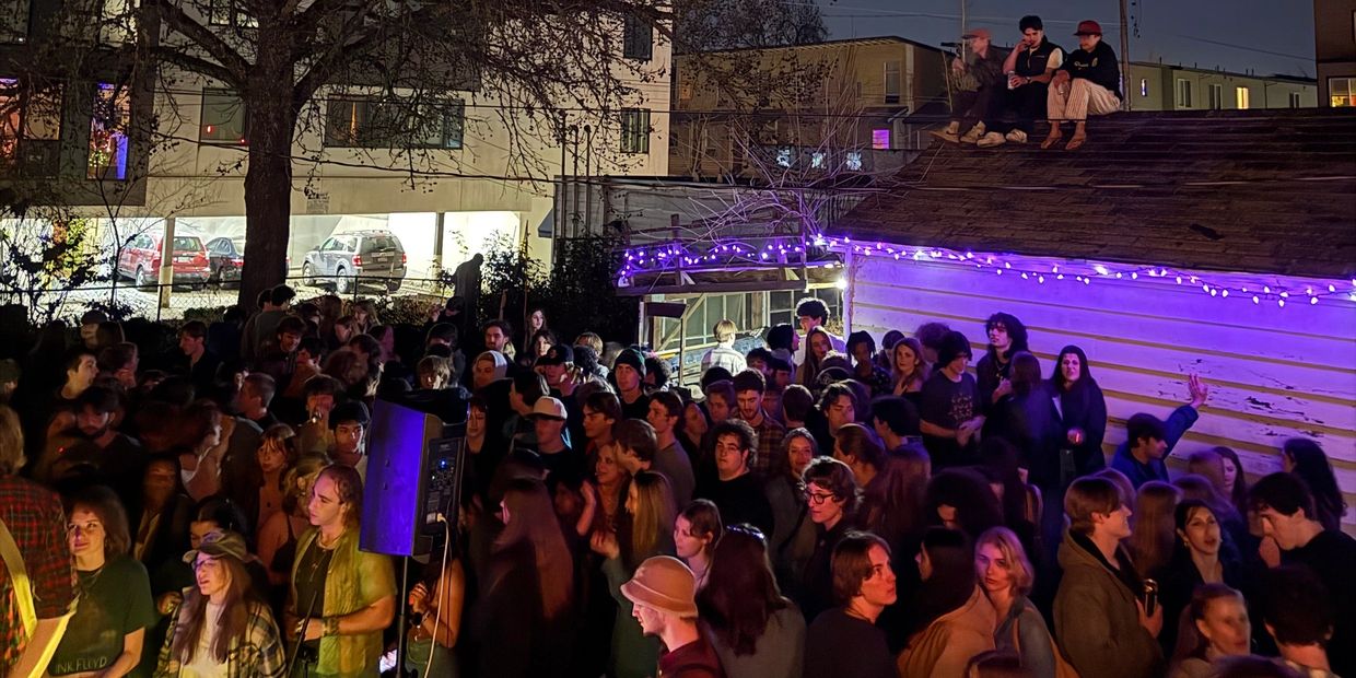 A crowded outdoor party at night with people socializing under string lights.