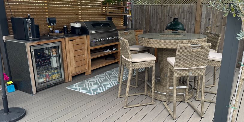 Modern custom outdoor kitchens and dining area with wicker chairs and a round table. The perfect outdoor cooking space