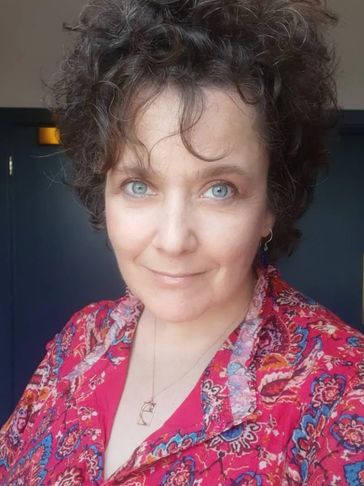 Woman with curly hair wearing a colorful shirt.