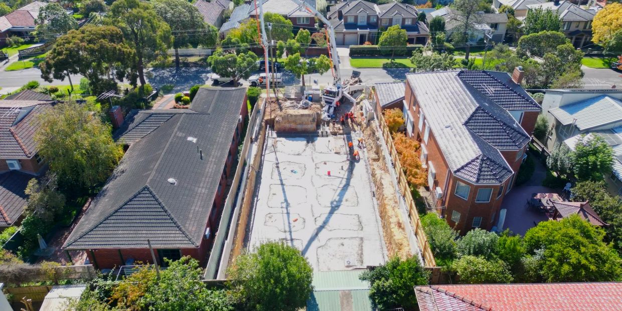 A construction site between two residential buildings in a suburban neighborhood.