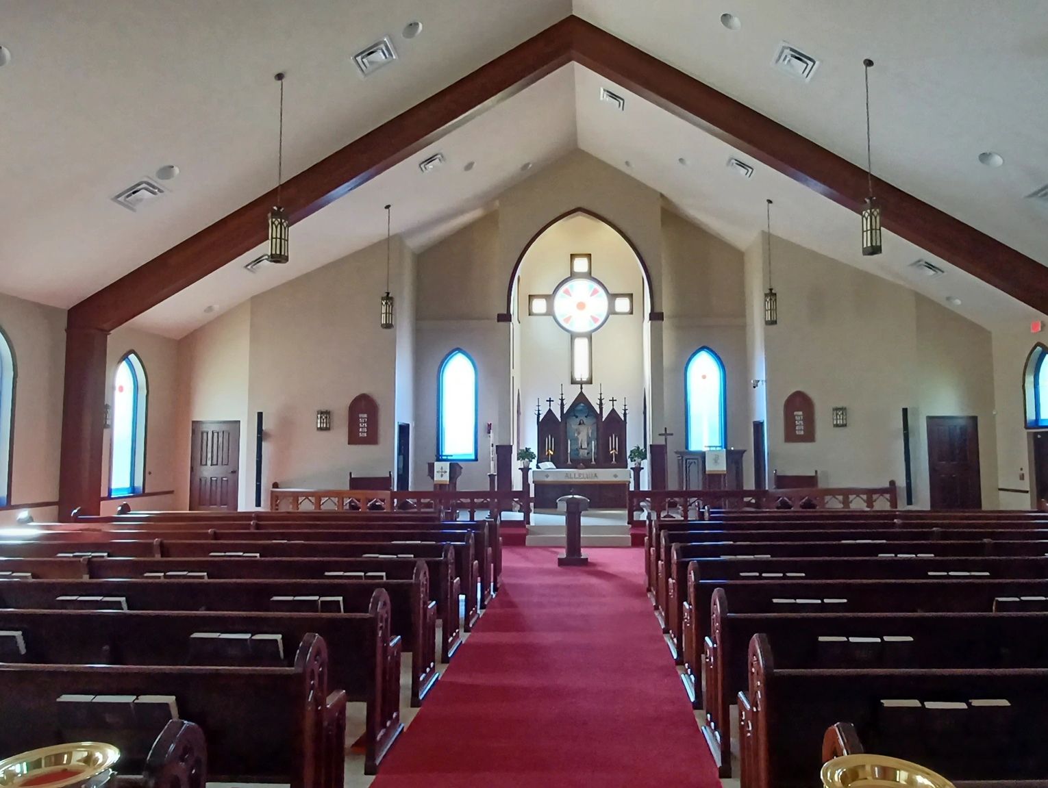Interior of a church with wooden pews and a red carpet aisle.