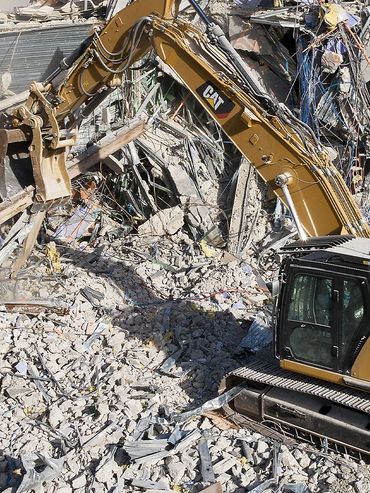Excavator demolishing a building amid rubble and debris.