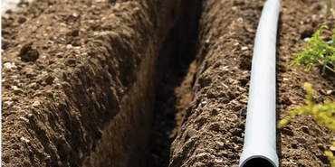 Trench being dug with pipe ready for installation.
