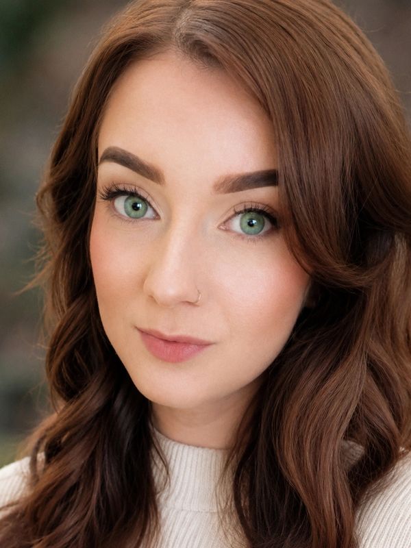 Portrait of a woman with green eyes and brown wavy hair.