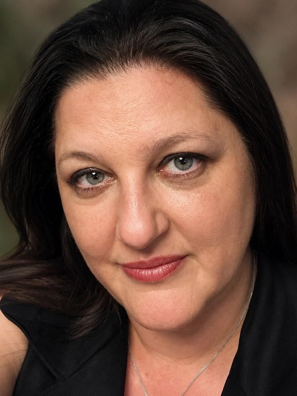 Close-up portrait of a woman with dark hair and green eyes.