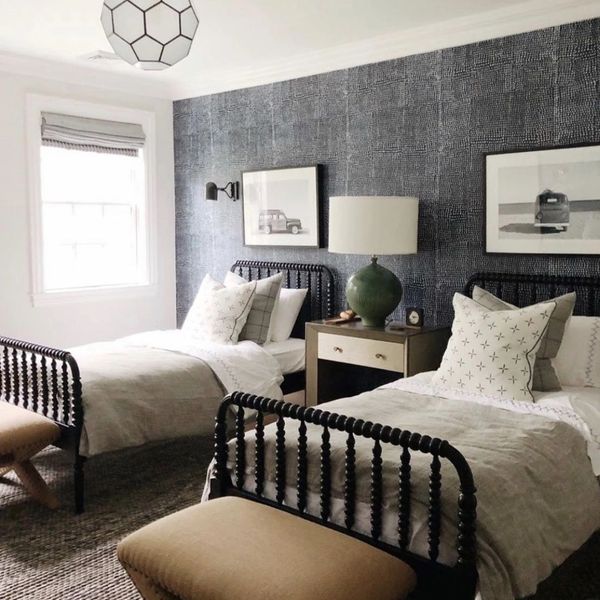 Cozy twin bedroom with dark textured accent wall and neutral bedding.