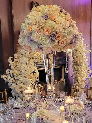 Tall floral centerpiece of blush, ivory, and lavender roses with cascading blooms and candles,