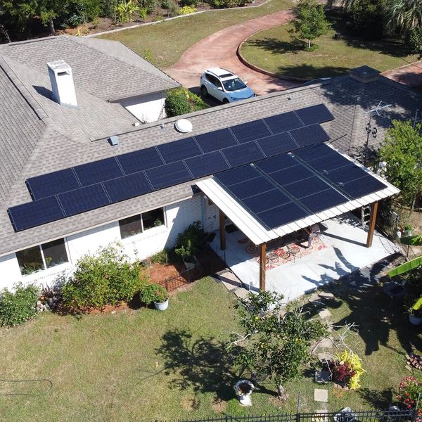 A house with solar panels installed on the roof and patio cover.