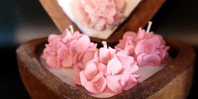 Heart-shaped wooden box with pink flower candles inside.