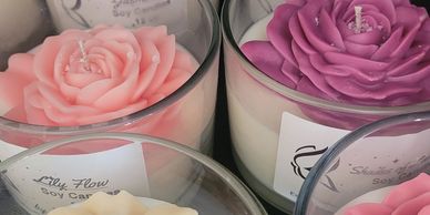 Elegant soy candles with rose-shaped tops in various colors inside clear glass holders.