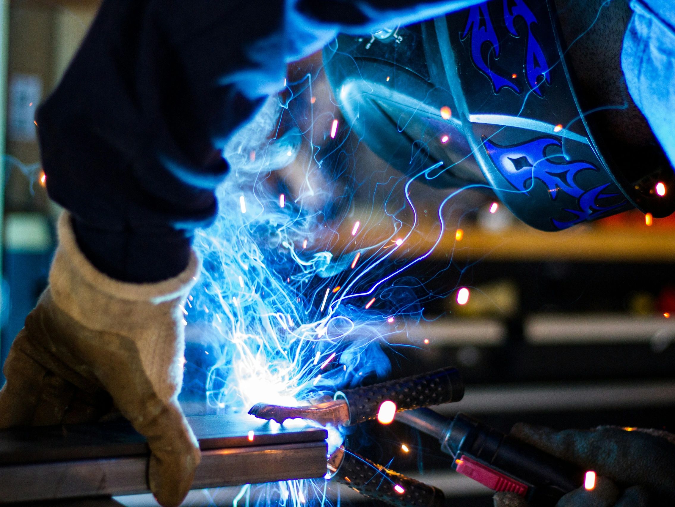 Close-up of a welder working with sparks and protective gear.