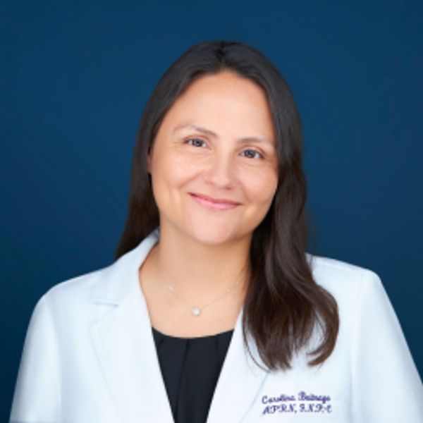 Smiling female doctor in white coat against blue background.