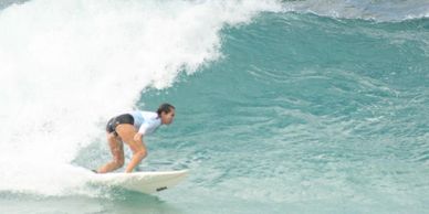 Surfer on a teal board catching a wave