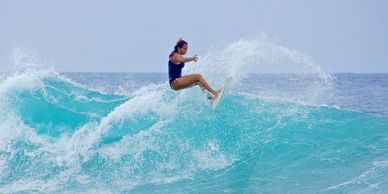 A surfer in motion, expertly maneuvering a teal surfboard along a breaking wave.