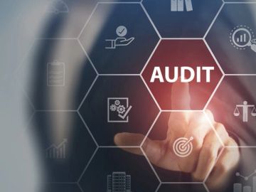 Hand pointing at the word 'AUDIT' on a digital interface.