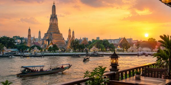Sunset view of temple by the river with boats.