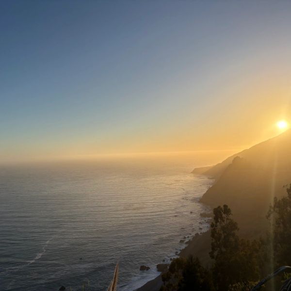 Sunset over a coastline with calm ocean waters.