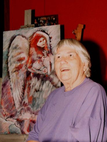 Inez Running-rabbit nex to one of her paintings.
